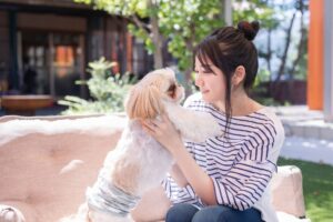 ドッグカフェで犬を抱き上げ、見つめ合う女性の写真
